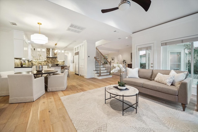 living room featuring crown molding, ceiling fan with notable chandelier, and light hardwood / wood-style flooring