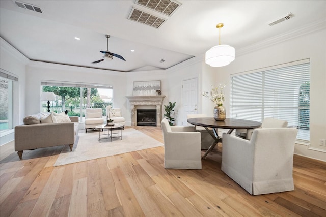 dining space with crown molding, ceiling fan, a fireplace, and light hardwood / wood-style floors