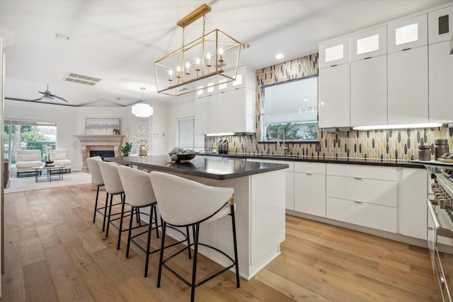 kitchen featuring white cabinetry, decorative light fixtures, tasteful backsplash, and a kitchen bar