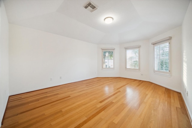 empty room featuring a tray ceiling and light wood-type flooring