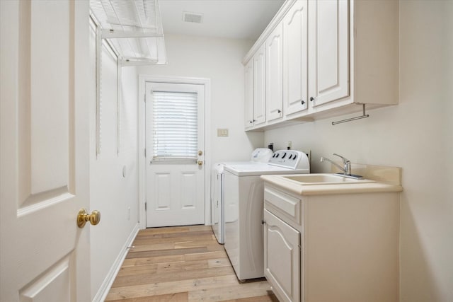 laundry area with sink, light hardwood / wood-style floors, cabinets, and washing machine and clothes dryer