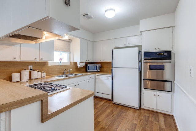 kitchen with sink, range hood, stainless steel appliances, light hardwood / wood-style floors, and white cabinets