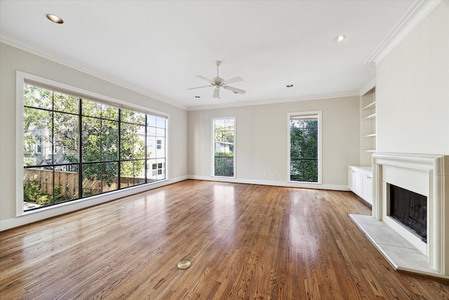 unfurnished living room featuring crown molding, hardwood / wood-style flooring, built in shelves, and ceiling fan