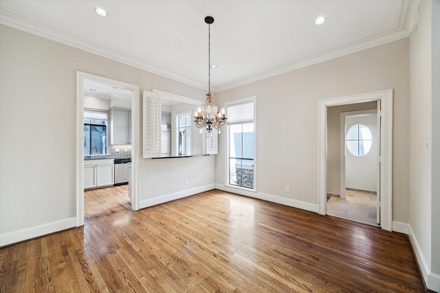 unfurnished dining area with a chandelier, ornamental molding, light hardwood / wood-style floors, and sink