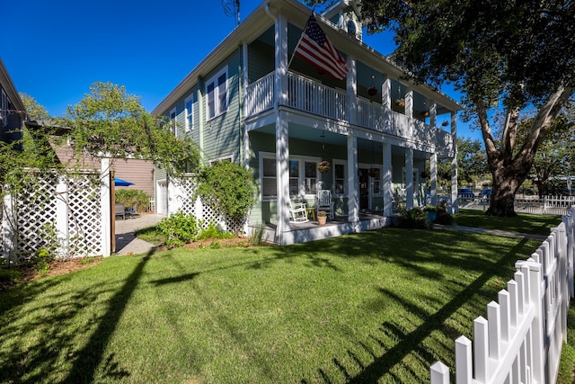 rear view of house featuring a lawn and a balcony