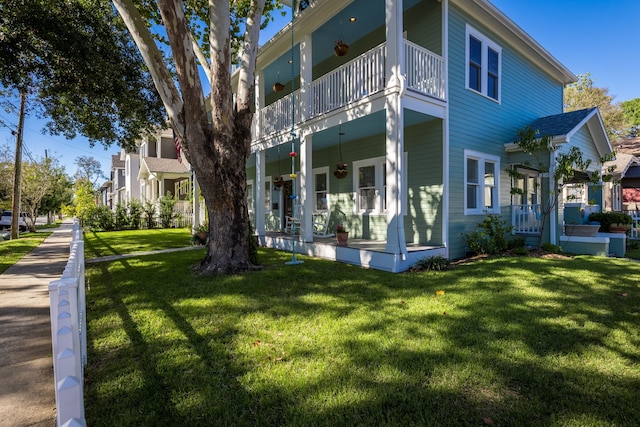 view of side of property with a balcony, a porch, and a lawn