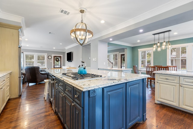 kitchen featuring stainless steel gas cooktop, light stone counters, dark hardwood / wood-style floors, pendant lighting, and a large island