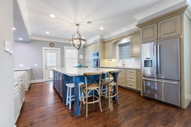 kitchen with dark hardwood / wood-style floors, cream cabinets, a center island, stainless steel appliances, and light stone countertops