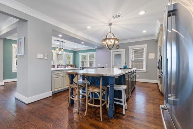 kitchen with pendant lighting, appliances with stainless steel finishes, an inviting chandelier, a center island, and light stone counters