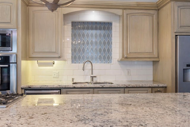 kitchen featuring sink, light stone counters, light brown cabinets, appliances with stainless steel finishes, and decorative backsplash