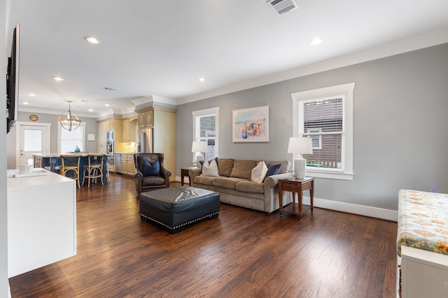 living room featuring dark wood-type flooring, ornamental molding, and an inviting chandelier