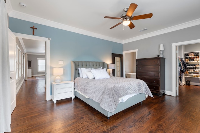 bedroom featuring crown molding, a walk in closet, dark hardwood / wood-style floors, and ceiling fan