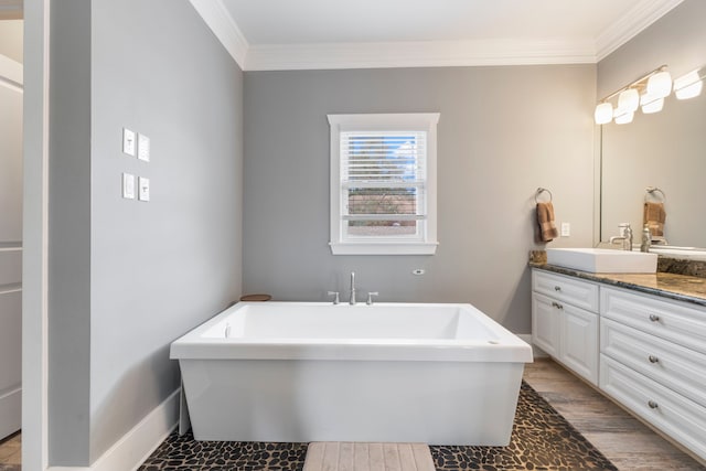 bathroom with crown molding, a tub, hardwood / wood-style floors, and vanity