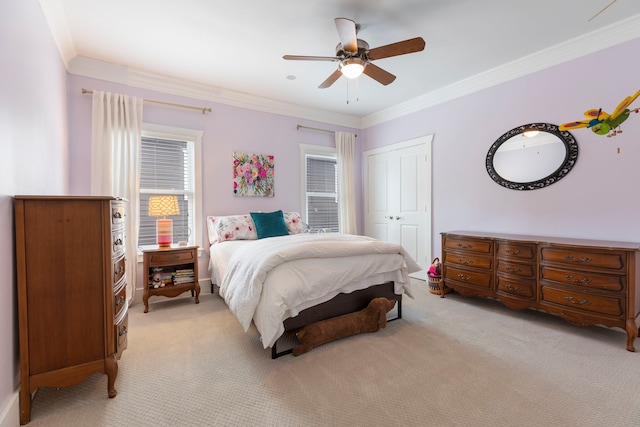 bedroom with crown molding, light colored carpet, ceiling fan, and a closet