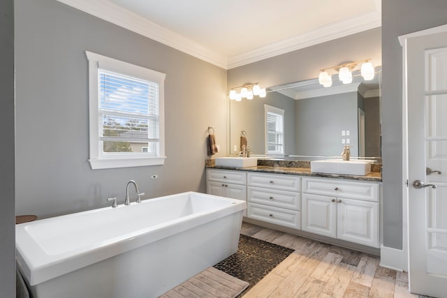 bathroom featuring vanity, hardwood / wood-style floors, ornamental molding, and a tub to relax in