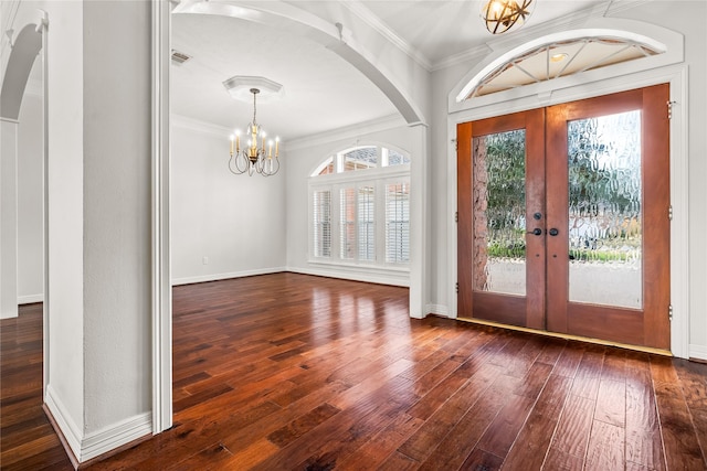 foyer entrance with dark hardwood / wood-style flooring, a notable chandelier, crown molding, and french doors