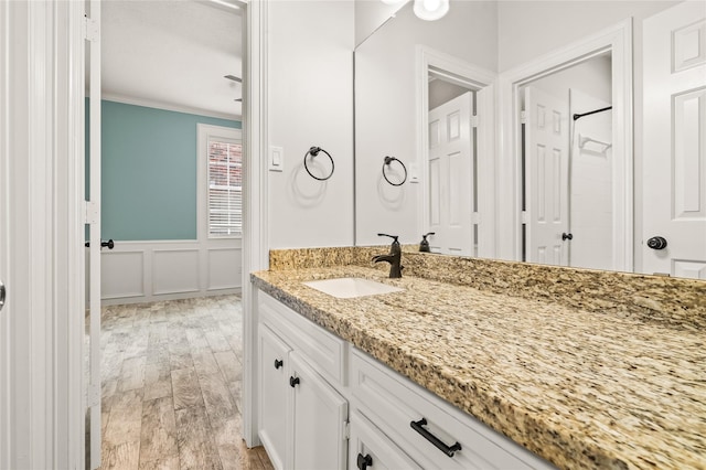 bathroom featuring crown molding, wood-type flooring, vanity, and walk in shower