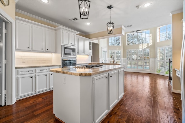 kitchen with white cabinetry, light stone countertops, pendant lighting, and stainless steel appliances