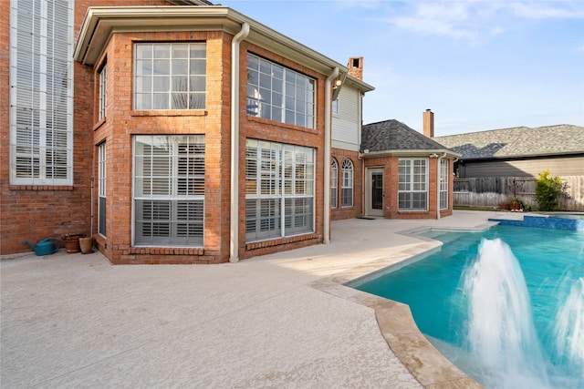 back of property with a fenced in pool, a patio, and pool water feature