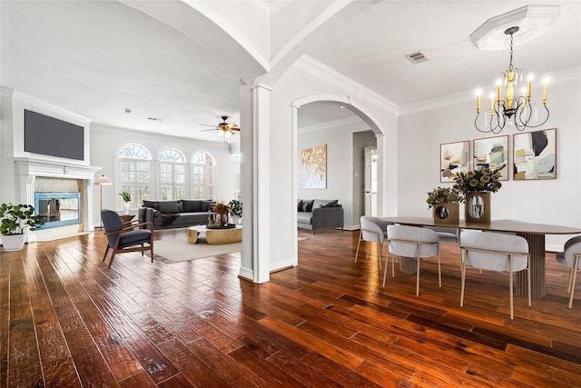 dining room with hardwood / wood-style floors, ceiling fan with notable chandelier, ornamental molding, and decorative columns