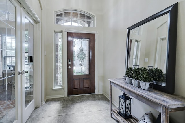 foyer with french doors, a towering ceiling, and light tile patterned floors