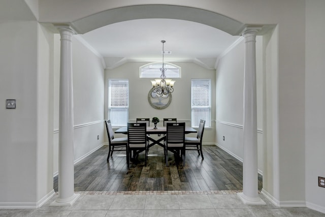 dining room featuring an inviting chandelier, hardwood / wood-style flooring, vaulted ceiling, and ornate columns