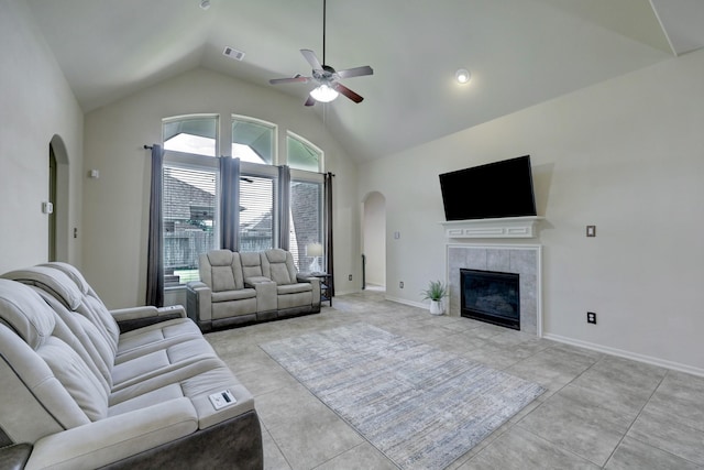 living room with high vaulted ceiling, a tile fireplace, ceiling fan, and light tile patterned flooring