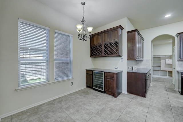 kitchen with dark brown cabinetry, light tile patterned floors, a notable chandelier, pendant lighting, and beverage cooler