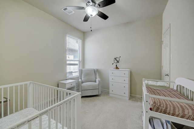 bedroom featuring ceiling fan, light carpet, and a crib