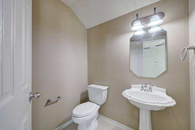 bathroom with tile patterned flooring, vaulted ceiling, and toilet