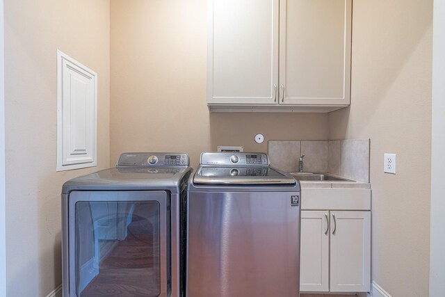 washroom with cabinets, independent washer and dryer, and sink