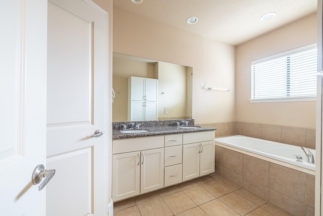 bathroom with tile patterned floors, vanity, and tiled tub