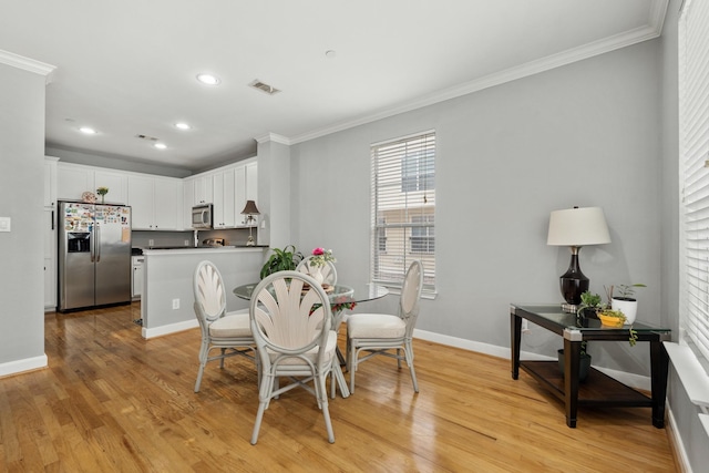 dining space featuring ornamental molding and light hardwood / wood-style flooring