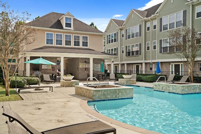 view of swimming pool featuring a hot tub, a patio, and pool water feature