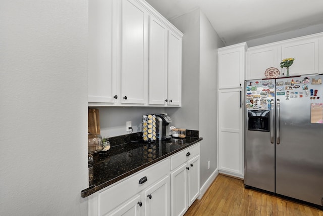 kitchen with white cabinetry, stainless steel fridge with ice dispenser, light hardwood / wood-style flooring, and dark stone counters