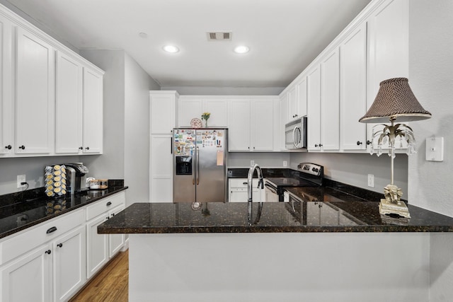 kitchen with white cabinetry, appliances with stainless steel finishes, and dark stone countertops