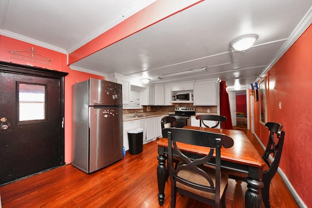 kitchen with crown molding, stainless steel appliances, hardwood / wood-style flooring, and white cabinets