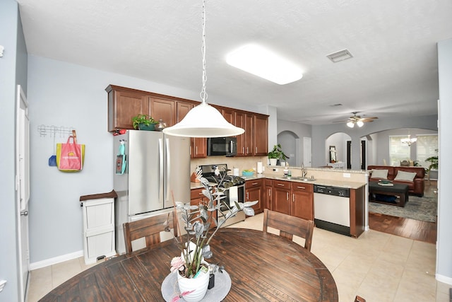 dining space with sink, light tile patterned floors, ceiling fan with notable chandelier, and a textured ceiling