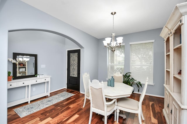 dining space featuring dark wood-type flooring and a notable chandelier