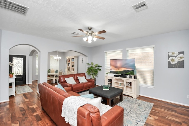 living room featuring dark hardwood / wood-style floors, ceiling fan with notable chandelier, and a textured ceiling