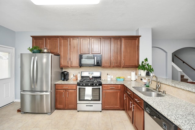 kitchen with sink, appliances with stainless steel finishes, tasteful backsplash, light stone countertops, and light tile patterned flooring