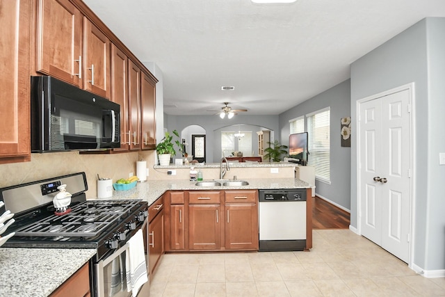 kitchen featuring sink, white dishwasher, kitchen peninsula, light stone countertops, and stainless steel range with gas stovetop