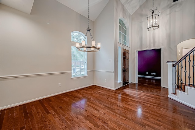 entrance foyer featuring a chandelier, high vaulted ceiling, baseboards, stairs, and wood finished floors