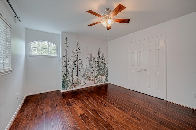 unfurnished bedroom with hardwood / wood-style floors, ceiling fan, baseboards, and a closet