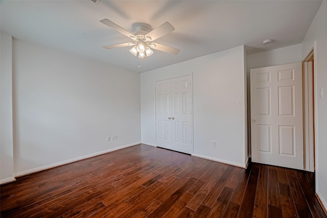 unfurnished bedroom with a closet, dark wood finished floors, baseboards, and a ceiling fan