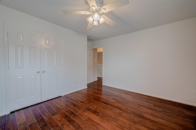 unfurnished bedroom with wood finished floors, a closet, baseboards, and a ceiling fan