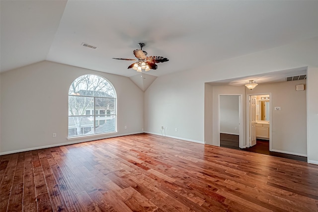 empty room with wood finished floors, a ceiling fan, vaulted ceiling, and baseboards