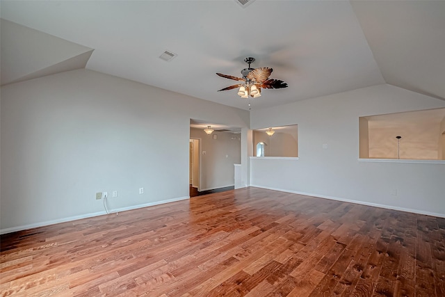 empty room with a ceiling fan, vaulted ceiling, wood finished floors, and baseboards
