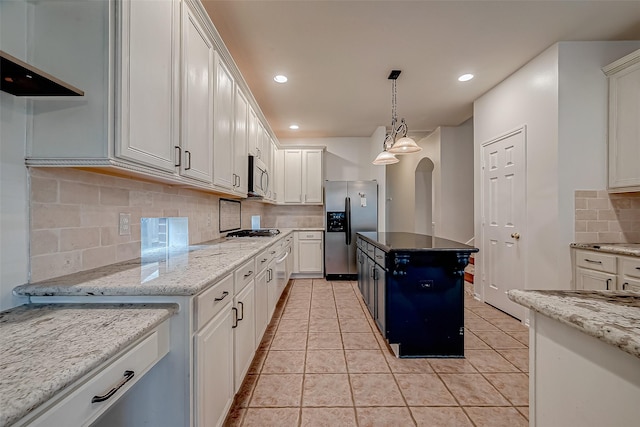 kitchen with appliances with stainless steel finishes, decorative backsplash, hanging light fixtures, arched walkways, and white cabinetry
