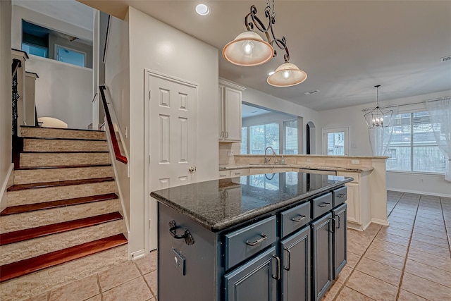 kitchen with a sink, a center island, baseboards, a chandelier, and a peninsula